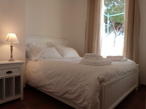 A neatly made bed with white linens and a stack of folded towels.