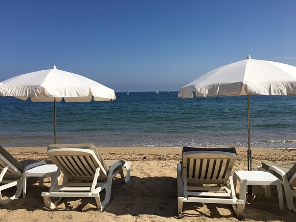 A beach with white umbrellas and lounge chairs.