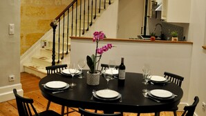 Un comedor con una mesa negra dispuesta para seis personas, una pared de piedra y una escalera.