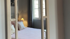 Un dormitorio con cama, un espejo grande y dos lámparas colgantes.