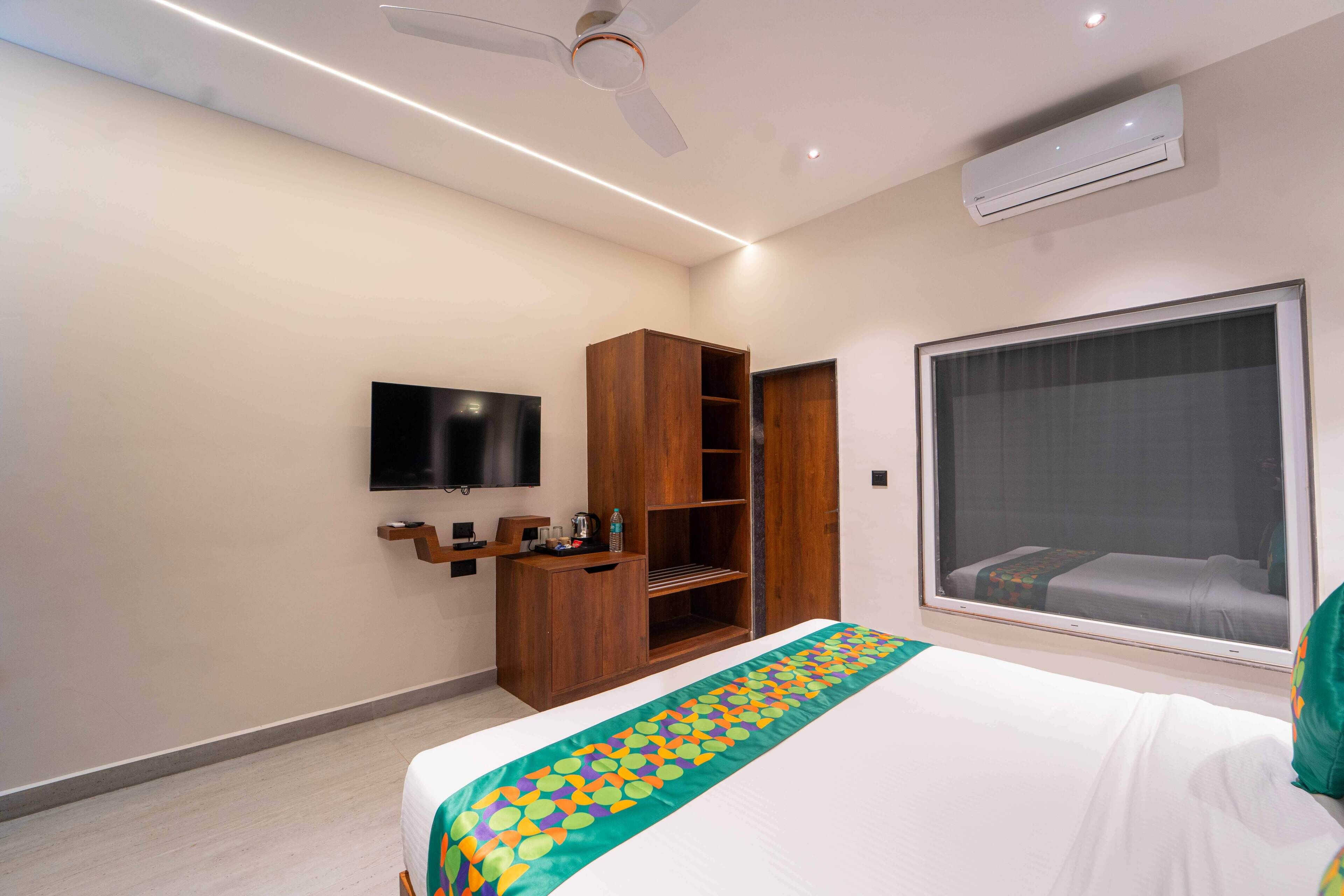 A hotel room with a bed, a TV, a wardrobe, and a window with a view.