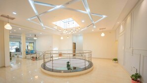A spacious lobby with a central glass railing, a skylight ceiling, and potted plants. - Treebo Winter Town Venna Lake (Mahabaleshwar)