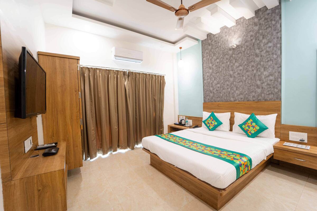 A hotel room with a wooden bed, a flat-screen TV, a desk, and a ceiling fan.