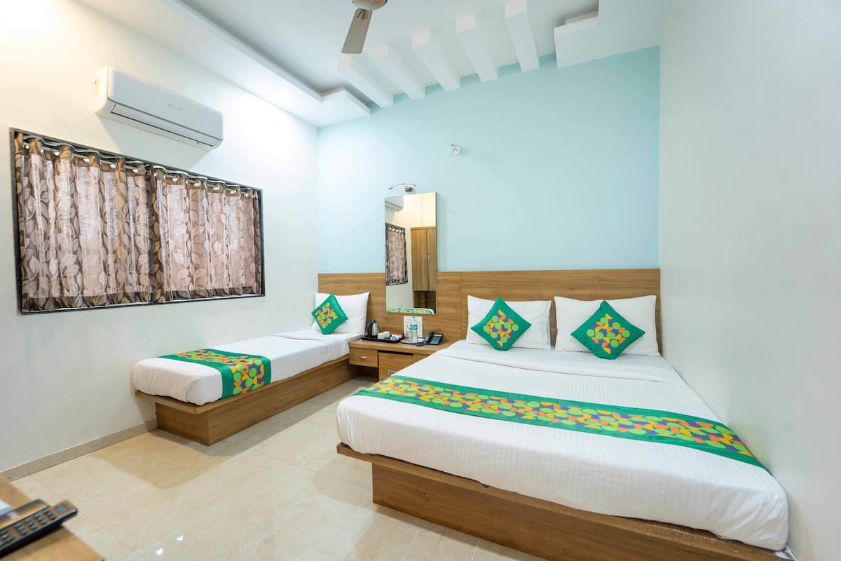 A hotel room with two beds, a large mirror, an air conditioning unit, and a window with curtains.