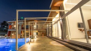 A modern hotel with a swimming pool, large windows, and a covered outdoor area. - Treebo Winter Town Venna Lake (Mahabaleshwar)