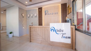 A hotel reception desk with a sign reading "Paradise Hotels & Resorts" and "Winter Town". - Treebo Winter Town Venna Lake (Mahabaleshwar)