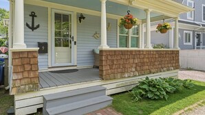 A house with a porch, a door, a mailbox, and a number sign.