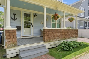 A house with a porch, a door, a mailbox, and a number sign.