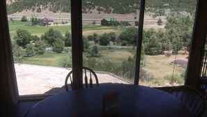 Ein Zimmer mit großem Fenster und Blick auf eine ländliche Landschaft, darunter Felder, Bäume und ein Gebäude in der Ferne.
