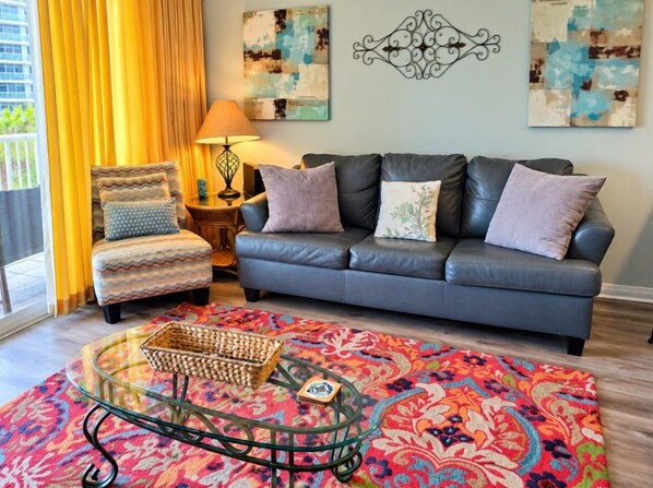 A living room with a sofa, armchair, and a glass coffee table with a woven basket.