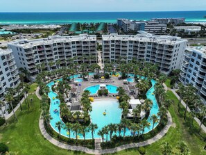 Un resort con varias piscinas, palmeras y vista al océano.