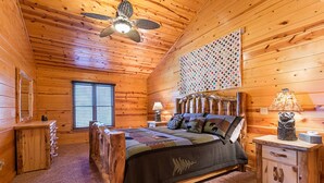 Un dormitorio acogedor tipo cabaña de madera con cama, mesita de noche, lámpara y cabecero de madera.