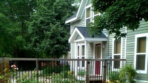 Ein zweistöckiges Haus mit Veranda, umgeben von einem Garten mit verschiedenen Pflanzen und Blumen.