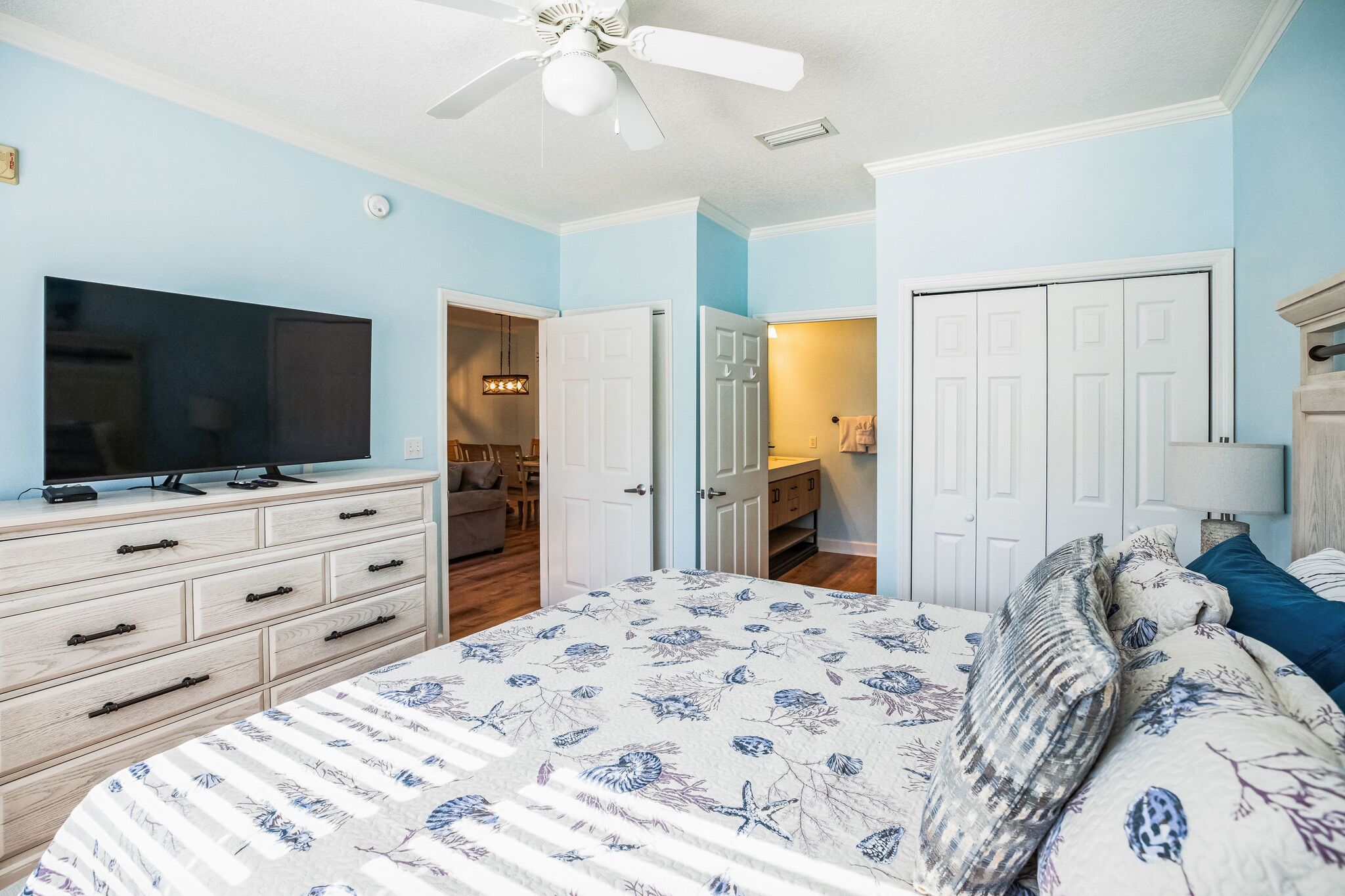 A bedroom with a bed, dresser, TV, and closet.