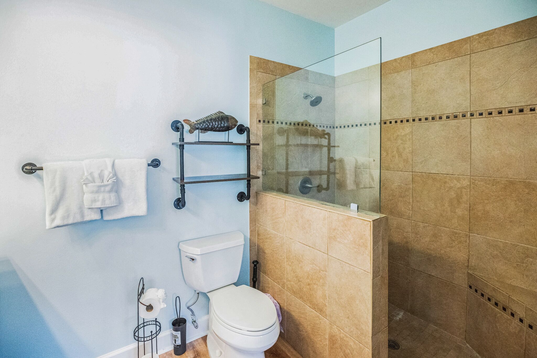 A bathroom with a toilet, a glass-enclosed shower, and a towel rack.