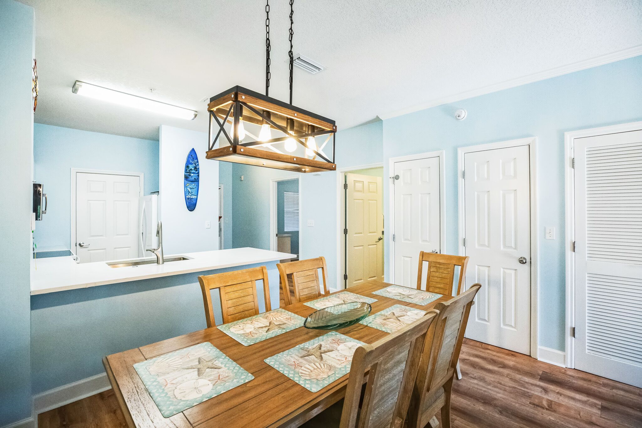 A dining area with a wooden table, chairs, and a hanging light fixture.
