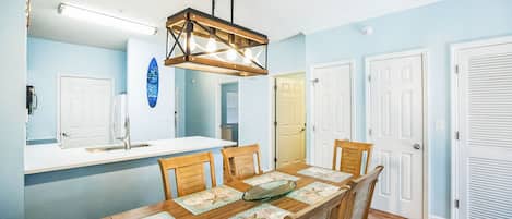 A dining area with a wooden table, chairs, and a hanging light fixture.