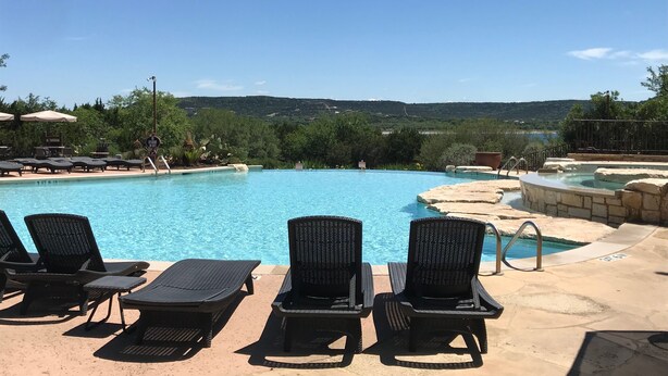 En swimmingpool med solstolar och utsikt över kullar.