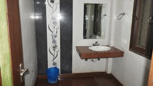 A bathroom with a sink, mirror, and shower. - JKM Palace (New Delhi)