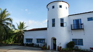 Un edificio blanco con una torre redonda, varias ventanas y un balcón.