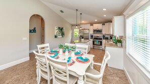 A dining area with a white table set for six, surrounded by white chairs. - Caribbean Reef! Cozy Pool Home Near Gulf! (Holmes Beach)