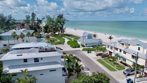 A coastal residential area with houses, a beach, and a clear view of the ocean. - Beautiful luxury home! Pool, rooftop deck and steps from the beach! (Holmes Beach)