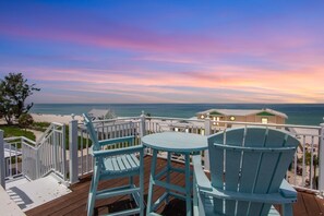 A deck with two chairs and a table overlooking a beach and ocean. - Beautiful luxury home! Pool, rooftop deck and steps from the beach! (Holmes Beach)