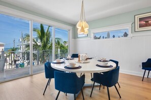 A dining area with a round table, blue chairs, and a view of the ocean. - Beautiful luxury home! Pool, rooftop deck and steps from the beach! (Holmes Beach)