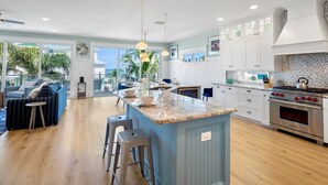 Une cuisine spacieuse dotée d’un grand îlot central, d’appareils électroménagers modernes et offrant une vue sur l’extérieur.