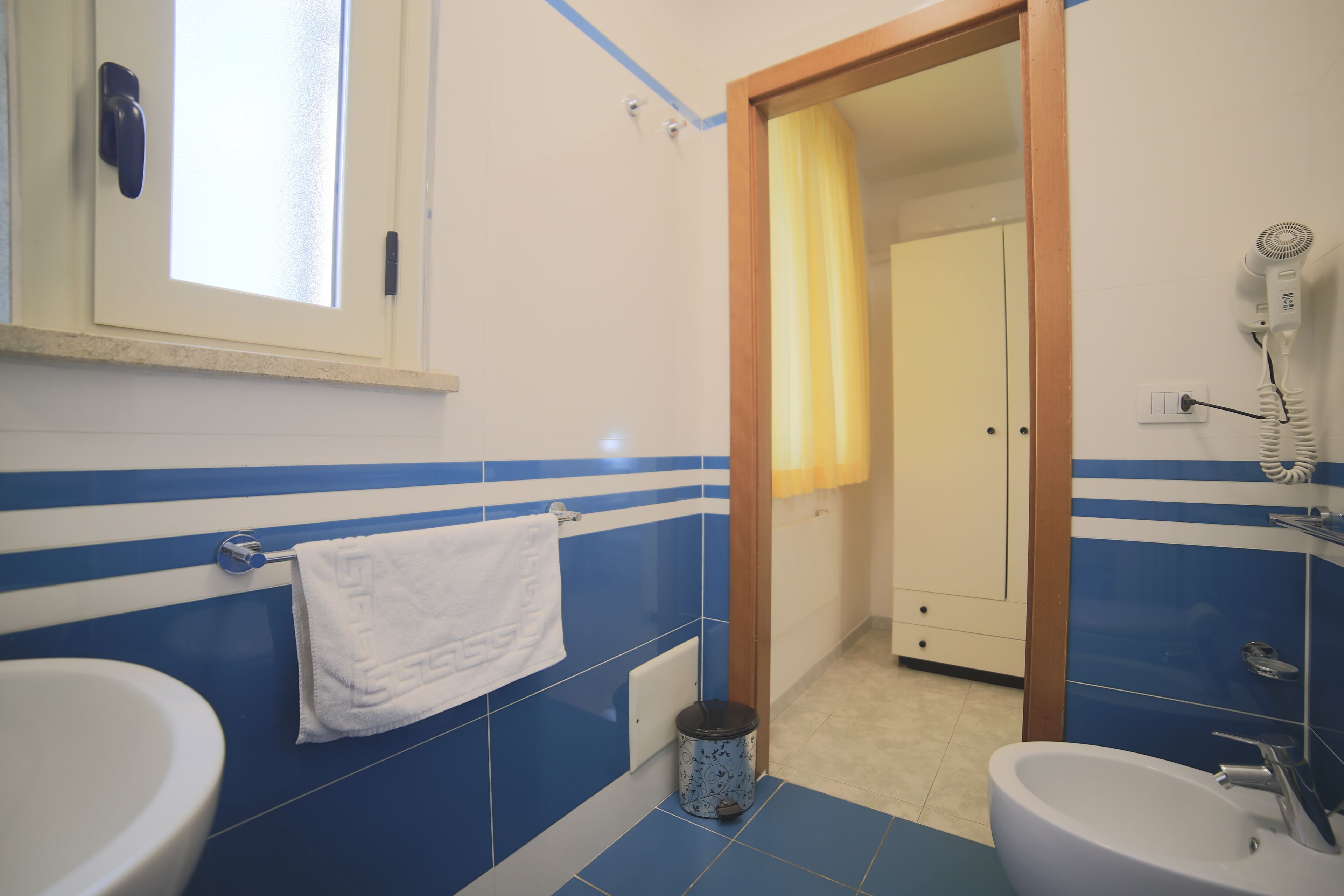 A bathroom with two sinks, a mirror, a towel rack, a toilet, and a shower area.