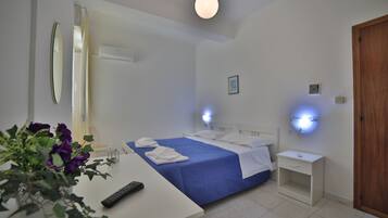 Habitación de hotel con cama, mesita de noche y un escritorio pequeño con un control remoto.