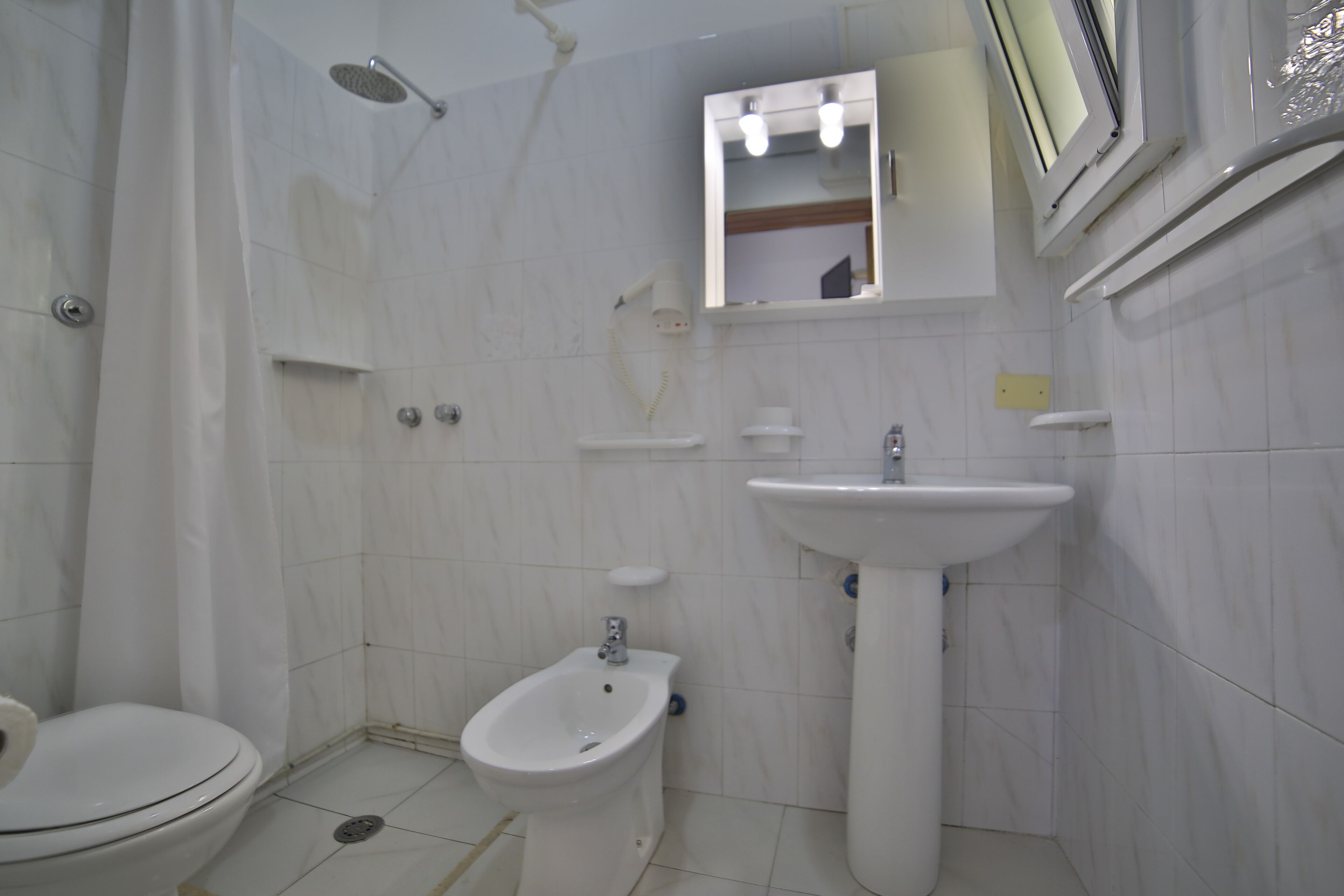 Une salle de bain comprenant des toilettes, un bidet, un lavabo et une douche.