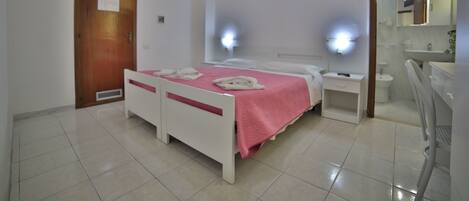 Habitación de hotel con cama, mesitas de noche, un espejo y un baño con lavabo e inodoro.