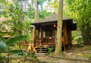 A wooden cabin with a thatched roof, surrounded by dense forest. - Barefoot at Havelock (Port Blair)