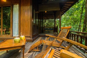 A wooden deck with a table and chairs, overlooking a lush forest. - Barefoot at Havelock (Port Blair)