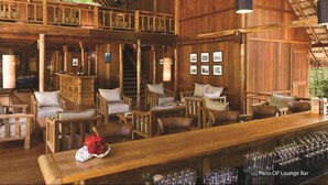 A wooden lounge bar with high ceilings and a thatched roof, featuring multiple seating areas and a bar counter. - Barefoot at Havelock (Port Blair)