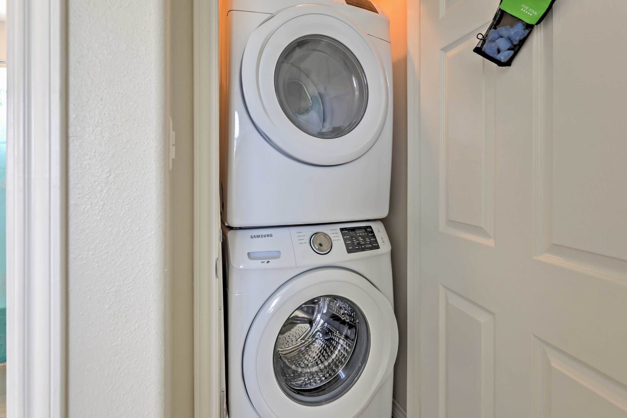 A stacked washer and dryer unit in a corner of a room.