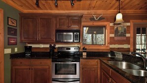 A kitchen with wooden cabinets, stainless steel appliances, a microwave, oven, and a sink. - Luxury Cabin: 3 Kings, Hot Tub, Fireplace, Lg Deck (Banner Elk)