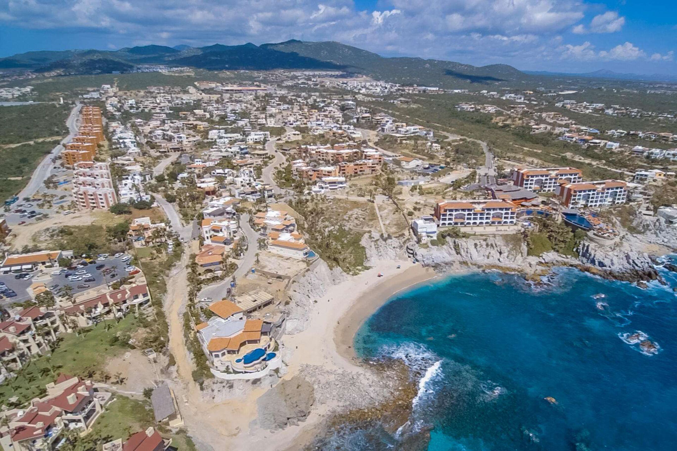 Vista aérea de un pueblo costero con edificios residenciales, una playa y un mar azul y despejado.