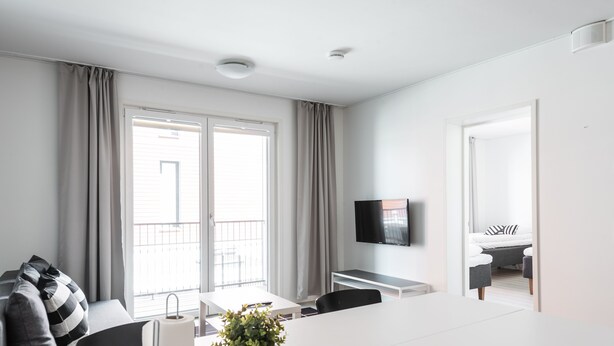 Una habitación de hotel moderna con un ventanal grande, un televisor de pantalla plana, un comedor y un balcón.