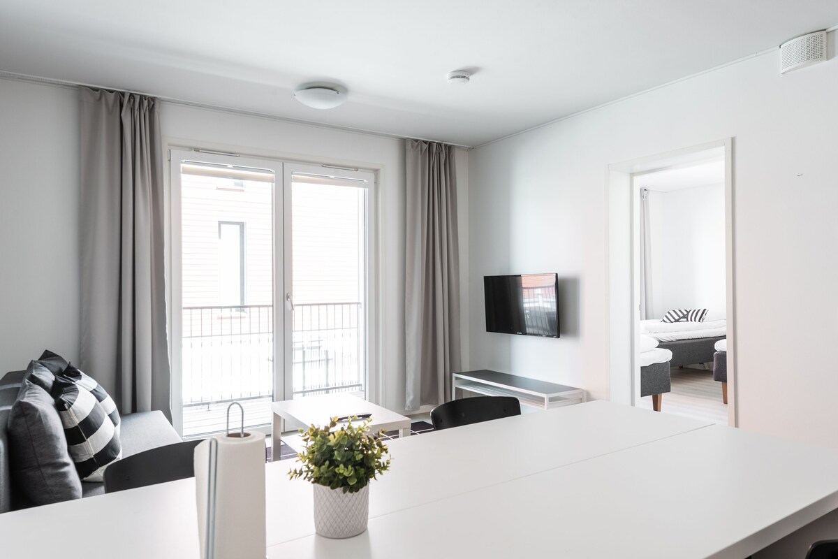 Une chambre d’hôtel moderne dotée d’une grande fenêtre, d’un téléviseur à écran plat, d’un coin repas et d’un balcon.