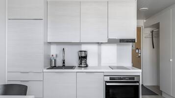 Cozinha moderna com armários brancos, máquina de café e forno embutido.