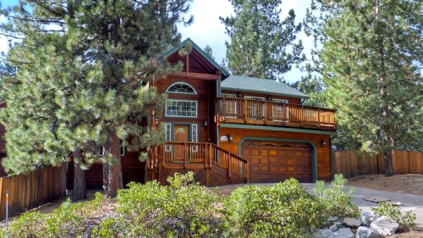 A log cabin with a wooden deck, a garage, and a fenced yard with trees and shrubs. - Two Master Family Home / Easy to Access Year-Round / Nearby Trails (South Lake Tahoe)