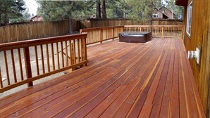 A wooden deck with a hot tub, wooden railings, and a view of a residential area with houses and trees. - Two Master Family Home / Easy to Access Year-Round / Nearby Trails (South Lake Tahoe)
