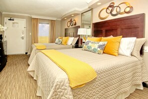 A hotel room with two beds, a large mirror, and a view of the sky through the window.