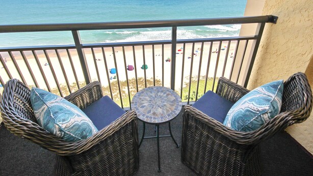 Ein Balkon mit Korbmöbeln und Blick auf den Strand.