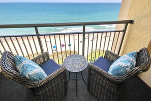 Ein Balkon mit Korbmöbeln und Blick auf den Strand.
