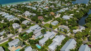 An aerial view of a coastal residential area with houses, a marina, and a clear view of the ocean.