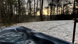 Un jacuzzi en un entorno nevado al aire libre, con un bosque de fondo.