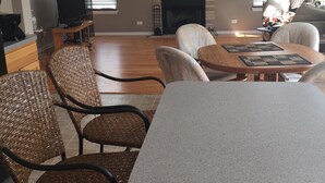 A living room with a fireplace, wicker chairs, a stone table, and a television on a stand. - Spacious and comfortable 5 bedroom, 2 1/2 bath two miles from down town Geneva (Geneva)